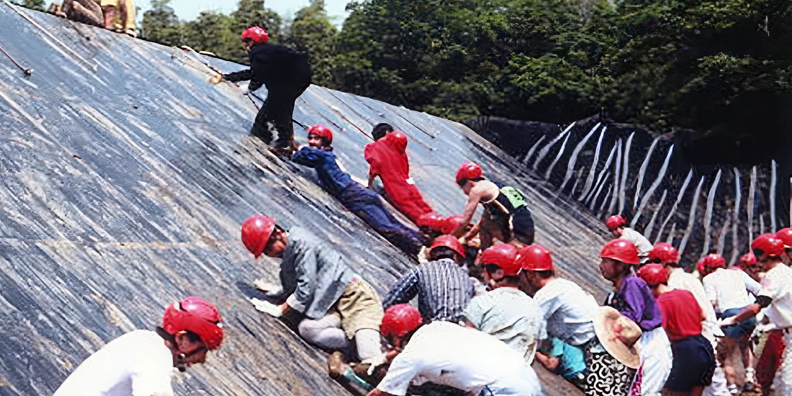 A group of contestants attempting to climb a sloped wall